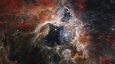 A photo of a nebula with swirling cream and orange clouds, and blue-tinted stars in the middle