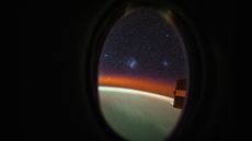 a view through a porthole in a spaceship showing the two Magellanic clouds in outer space