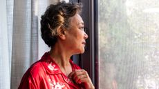 Older woman is shown staring out of a window