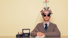 A man with a helmet on his head. He is dressed in retro sweater and tie with safety goggles waiting to measure brain waves.