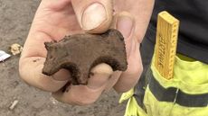 A man hands a tiny carved animal toy